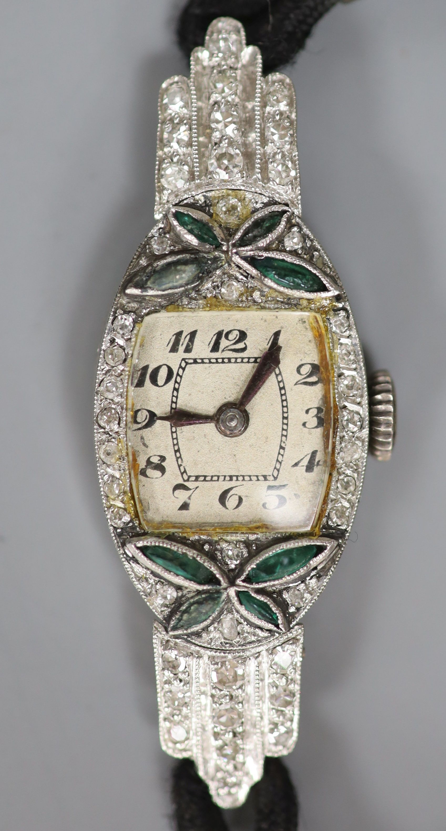 A lady's 1940's/1950's white metal (stamped platinum), emerald? and diamond set cocktail watch, on fabric strap, gross weight 14.3 grams.